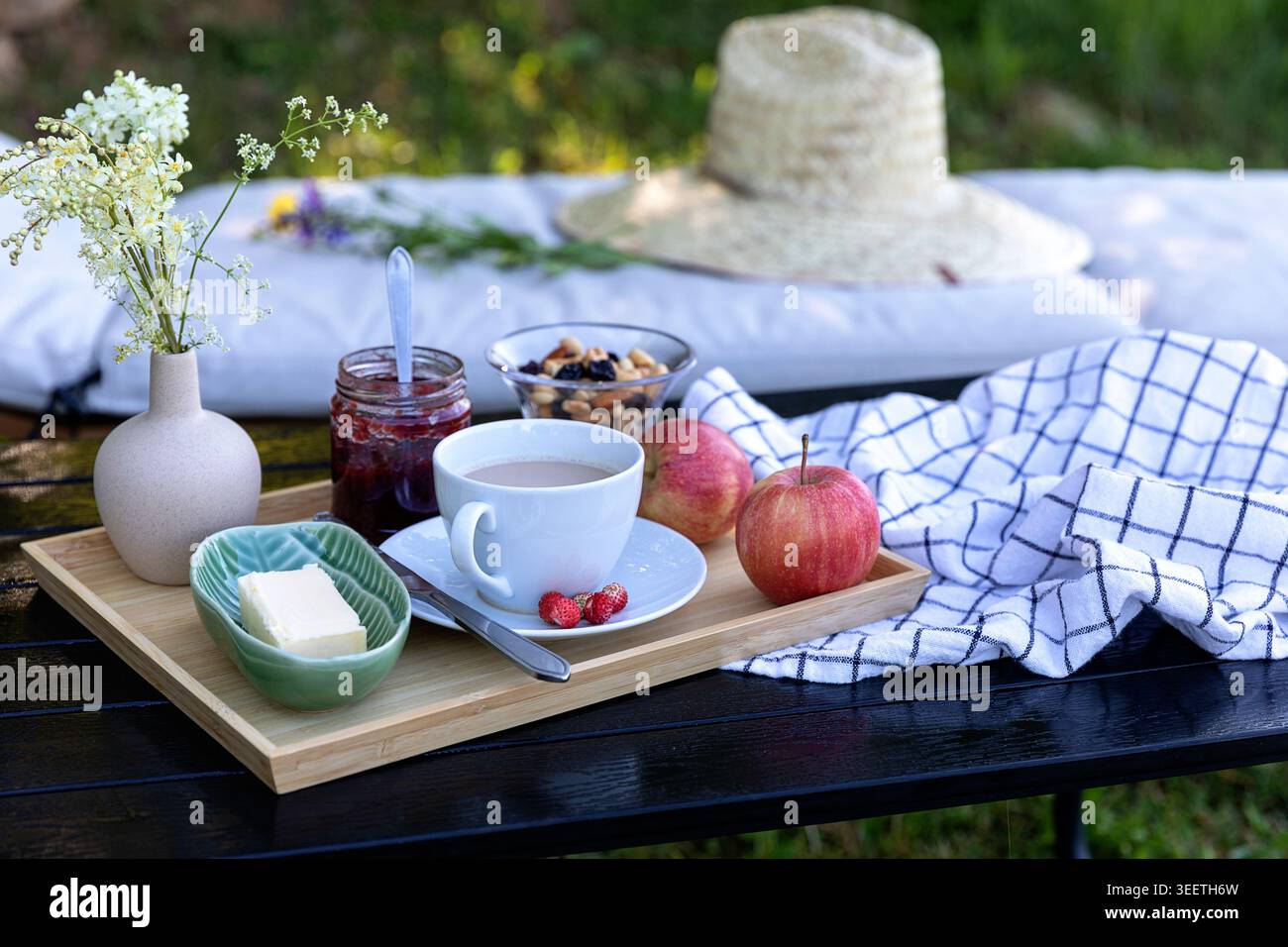 Una deliziosa colazione fatta in casa servita su un vassoio di legno rustico con caffè fresco, marmellata, burro e un bellissimo vaso di fiori di campo. Foto Stock