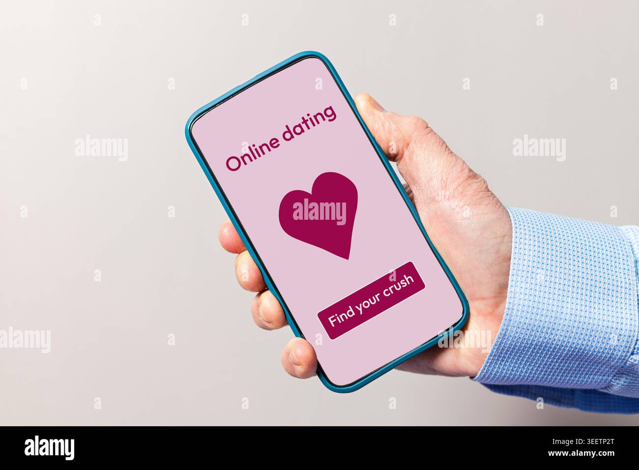 Mano che tiene in mano uno smartphone che visualizza un'app di incontri online con un cuore e trova il tuo pulsante di schiacciamento Foto Stock