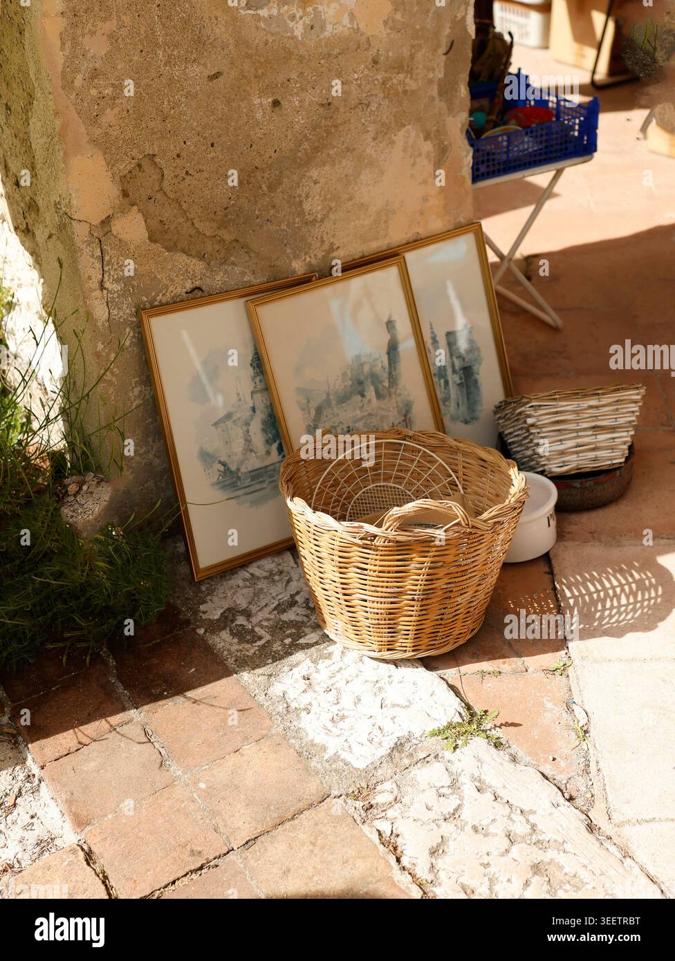 Antichi tesori del mercato delle pulci francese con cesti di vimini intrecciati a mano e schizzi di paesaggi blu. Autentico display brocante provenzale con cornici dorate Foto Stock