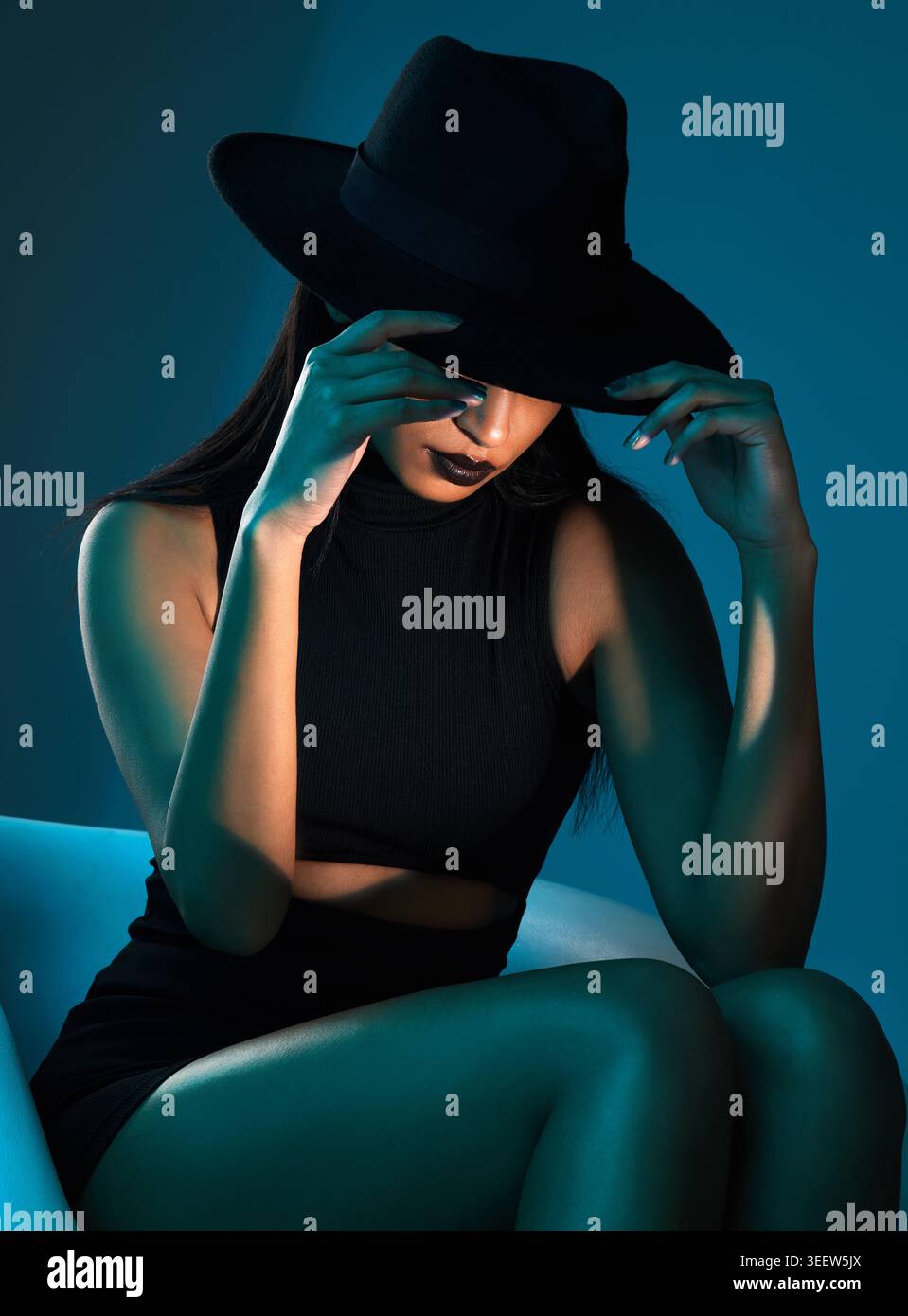 Cappello, misterioso e donna in studio con stile elegante, elegante o alla moda con bagliore. Estetica, elegante e segreta o nasconditi con la persona per Foto Stock