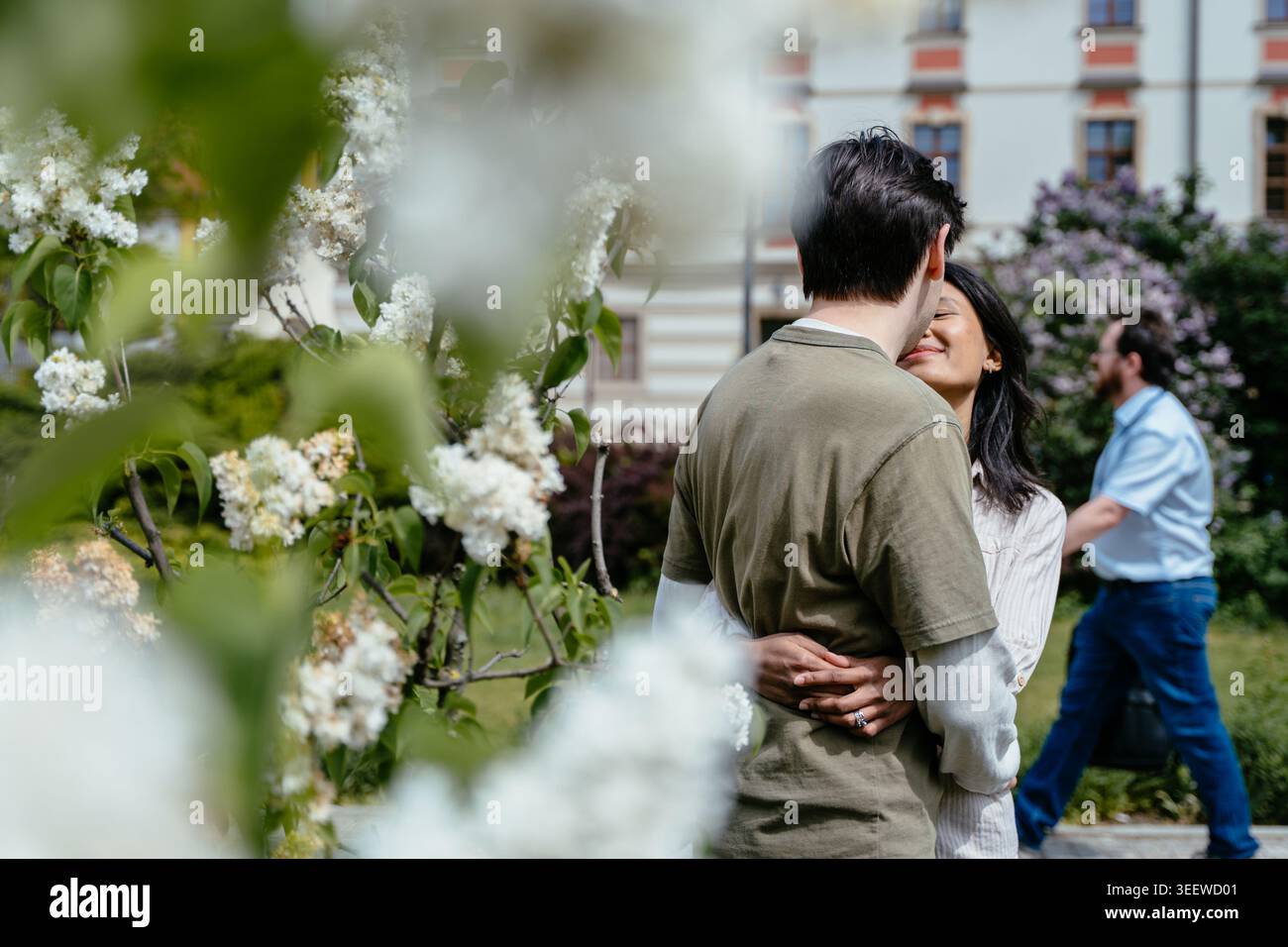 Primo piano di giovani coppie multiculturali che si baciano nel parco in fiore in primavera in Europa Foto Stock