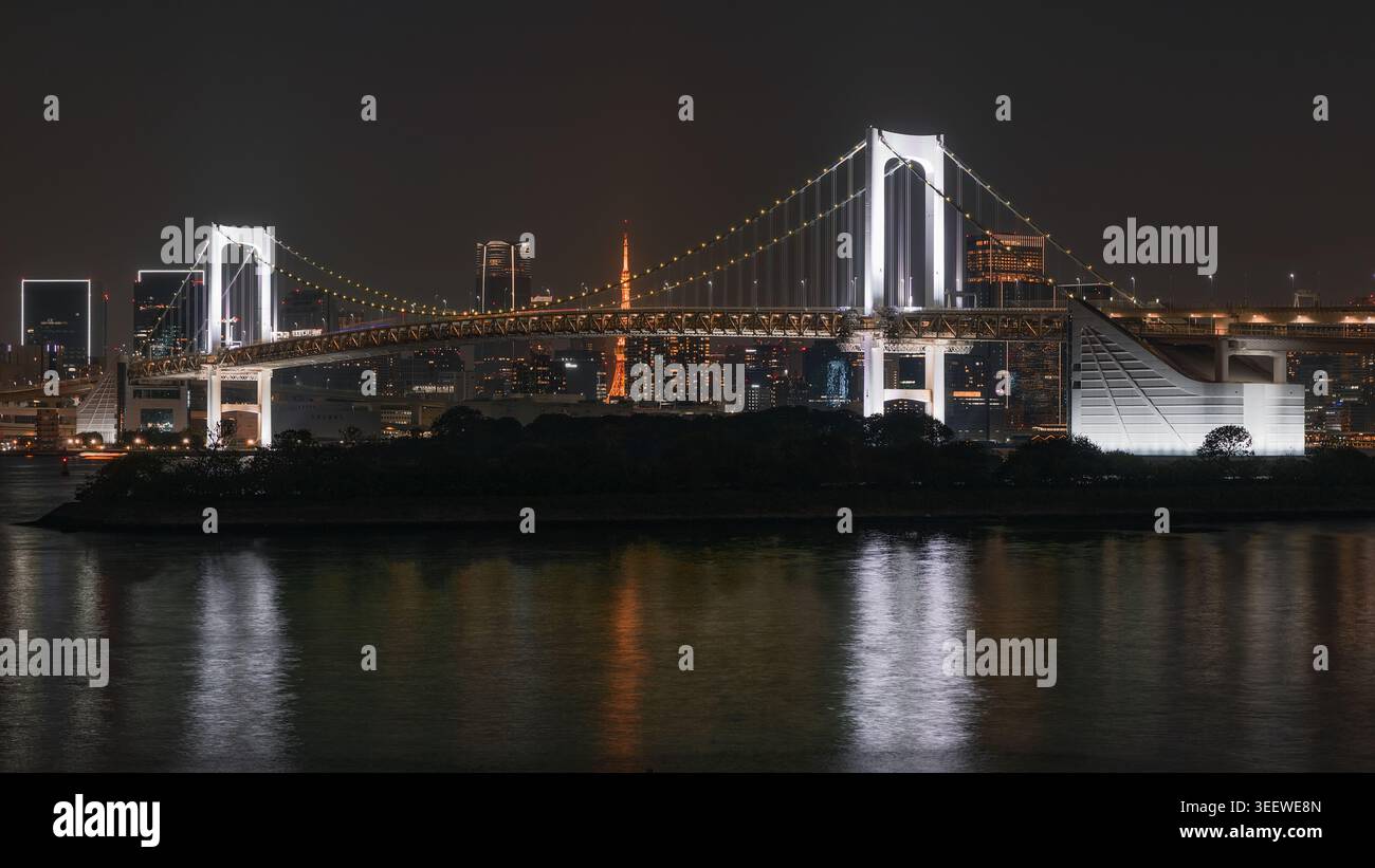 Vista notturna del ponte sospeso con luci della città e riflessi Foto Stock
