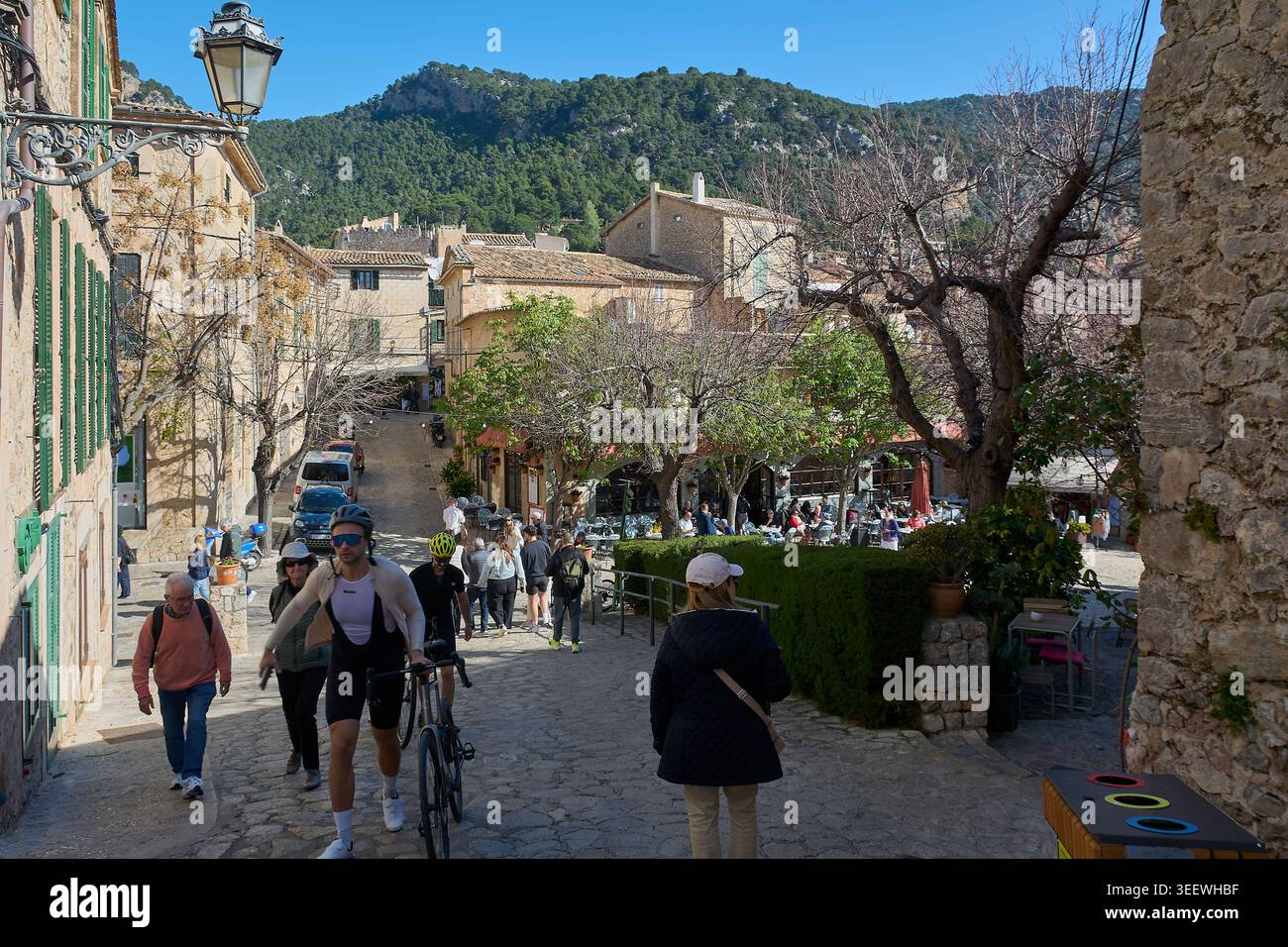 Maiorca, Spagna - 12 maggio 2026: Turisti e ciclisti esplorano le affascinanti strade acciottolate di Valldemossa, uno storico villaggio di montagna di Maiorca Foto Stock
