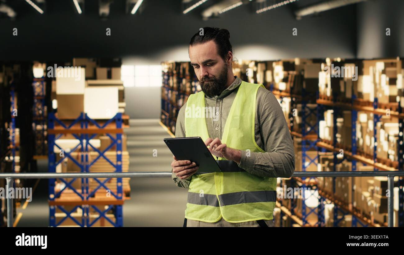 I dipendenti del magazzino controllano la logistica degli ordini sul tablet nel centro di evasione ordini, gestiscono i dettagli delle spedizioni e delle consegne rapide. Uomo che assicura pacchetti merci per l'industria dell'e-commerce, grandi imprese. Foto Stock