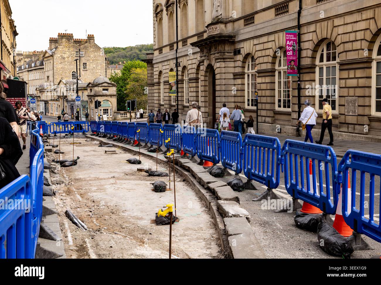 Lavori di costruzione di strade nella storica città di Bath lungo Bridge Street con barriere di plastica blu e pedoni a piedi Foto Stock