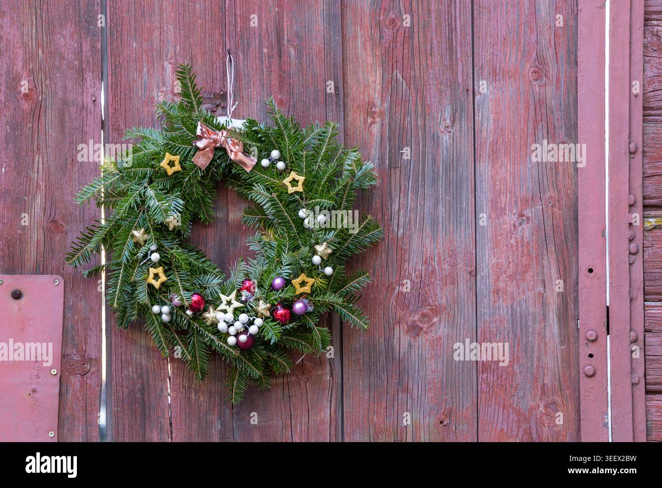 Corona di Natale con decorazioni appese su una vecchia porta di legno intemprata a Slavonice, Cechia Foto Stock