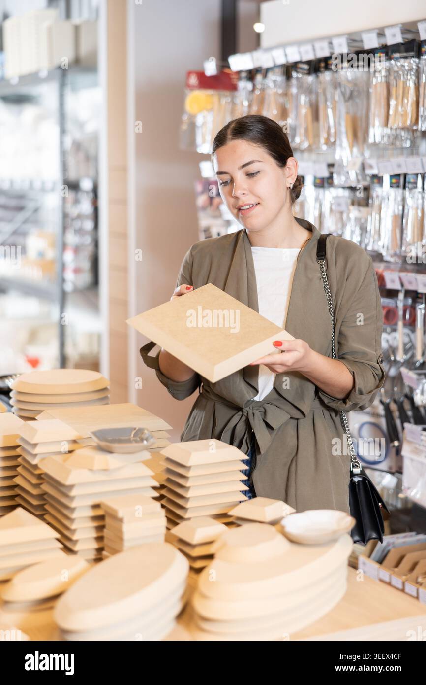 Nel negozio di ceramiche, positive Woman sceglie vari stampi in legno per il futuro stampaggio dell'argilla nella sua officina Foto Stock