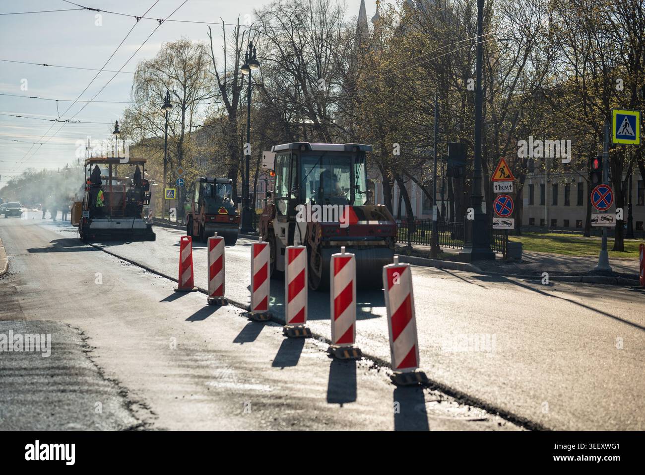 Manutenzione stradale primaverile in città, processo di pavimentazione su strada con macchinari pesanti che applicano nuovo asfalto. Foto Stock