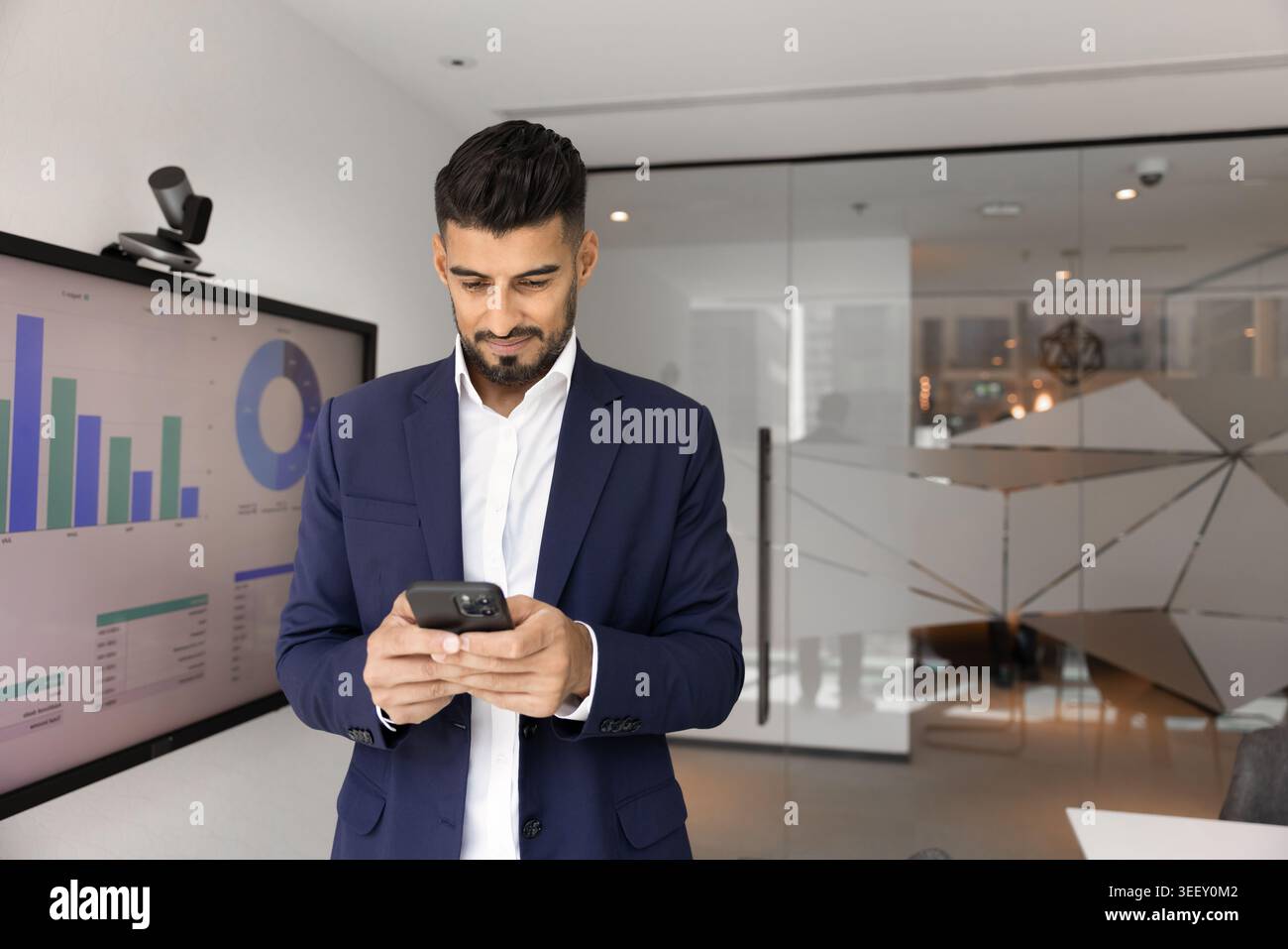 Un uomo d'affari indiano che legge un messaggio sullo smartphone Foto Stock