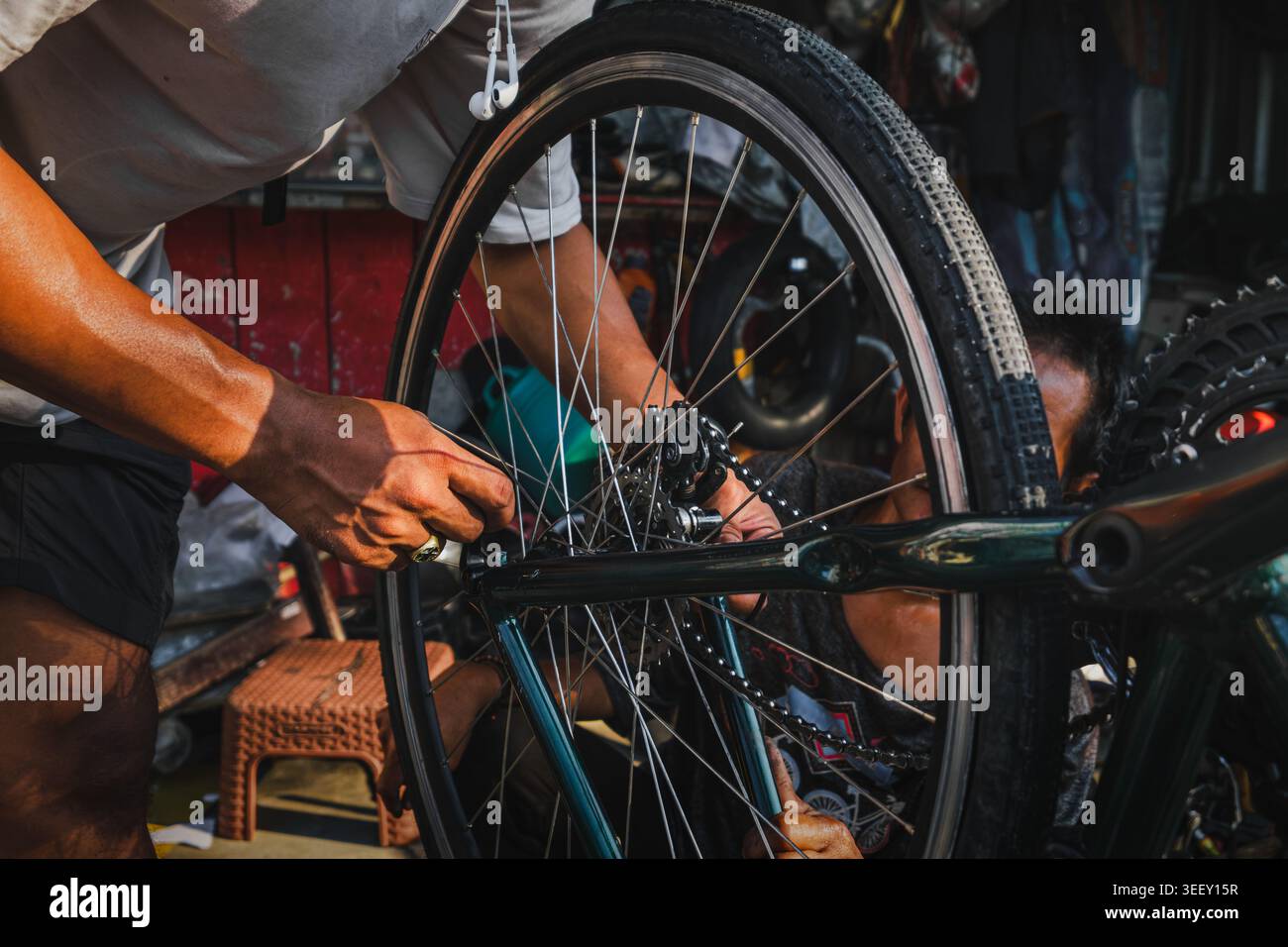 Le mani di un meccanico regolano la ruota posteriore e il deragliatore di una bicicletta. L'immagine acquisisce il lavoro del manuale tecnico. Foto Stock