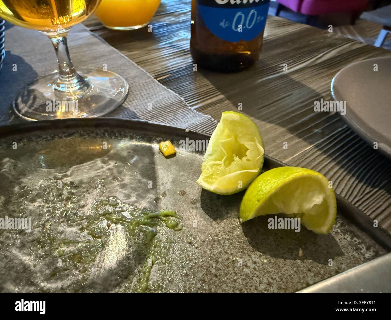 Riga, Lettonia - 2 maggio 2026: Tavolo da ristorante Moody con un piatto vuoto, spicchi di lime spremuto e bevande dopo un pasto finito. bancomat per cene informali Foto Stock