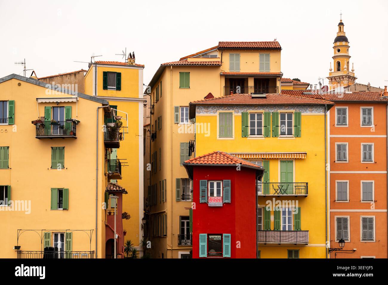 Mentone, Francia, 12 aprile 2026 Mentone, Francia, 12 aprile 2026 Una vista vibrante delle colorate facciate di Mentone, caratterizzato da uno stretto edificio rosso, persiane verdi Foto Stock