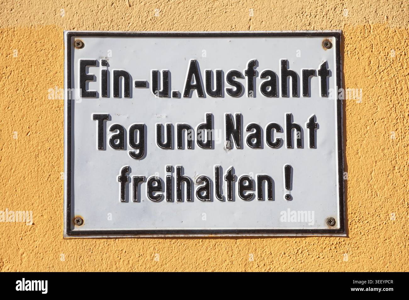 Schild Einfahrt und Ausfahrt Tag und Nacht freihalten an einer gelben Mauer, Deutschland Foto Stock