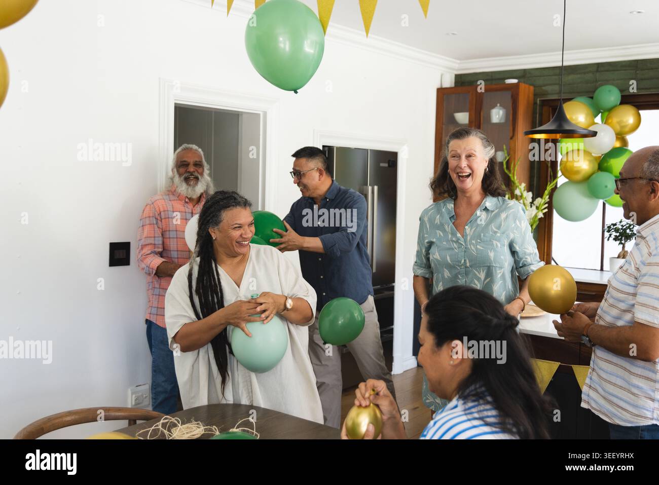 Sei ospiti che organizzano feste, organizzano palloncini verdi-dorati in cucina, la guida AR mostra garland Foto Stock
