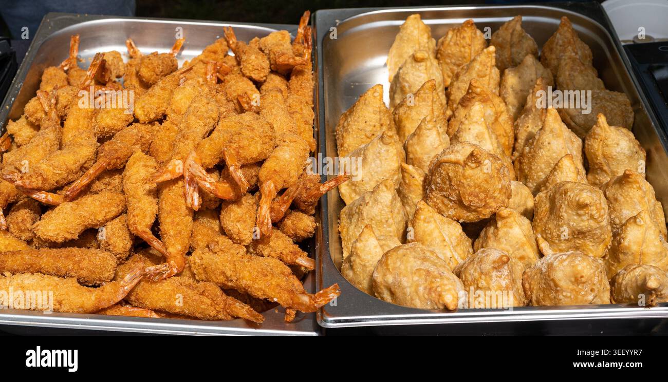 Gamberi fritti, gamberi impanati e gnocchi croccanti fritti. Samosas Golden Brown pronti da mangiare, festival del cibo di strada, delizie culinarie, pesce e spuntini Foto Stock