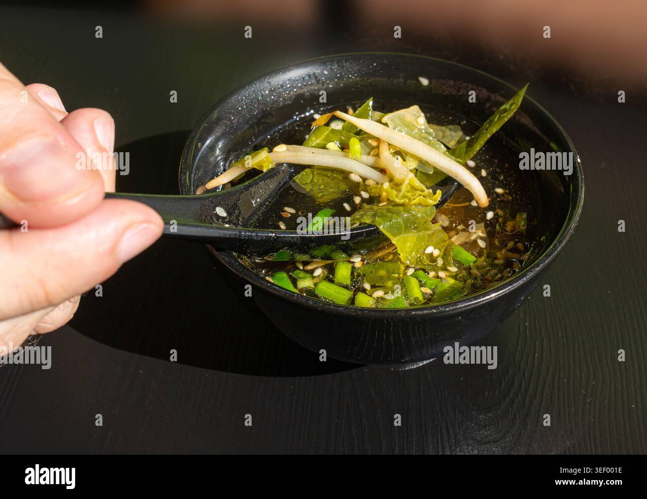 Brodo di pesce con verdure, semi di sesamo ed erbe aromatiche, brodo trasparente, ramen Shio, brodo di salmone, zuppa giapponese in ciotole nere Foto Stock