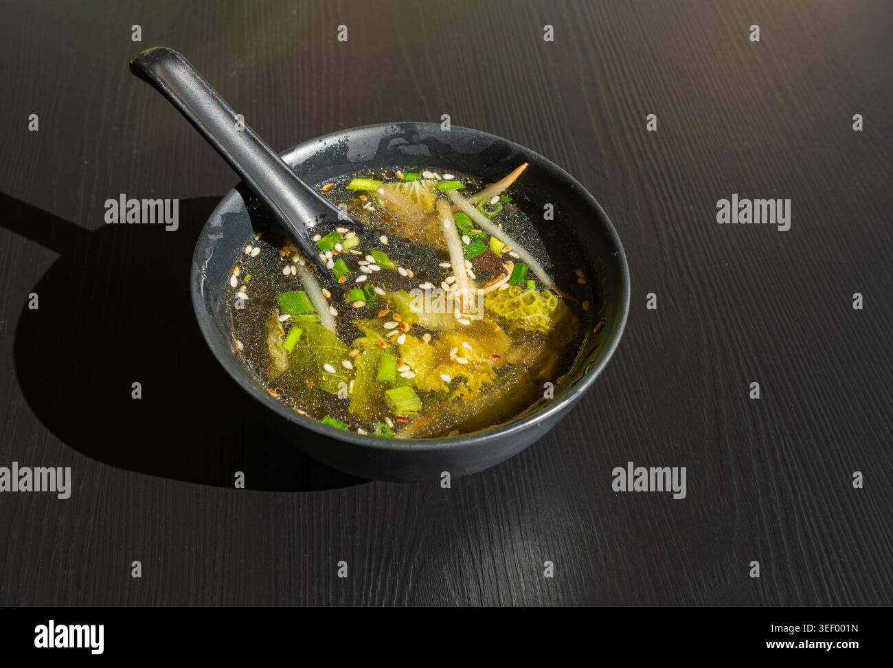 Brodo di pesce con verdure, semi di sesamo ed erbe aromatiche, brodo trasparente, ramen Shio, brodo di salmone, zuppa giapponese in ciotole nere Foto Stock
