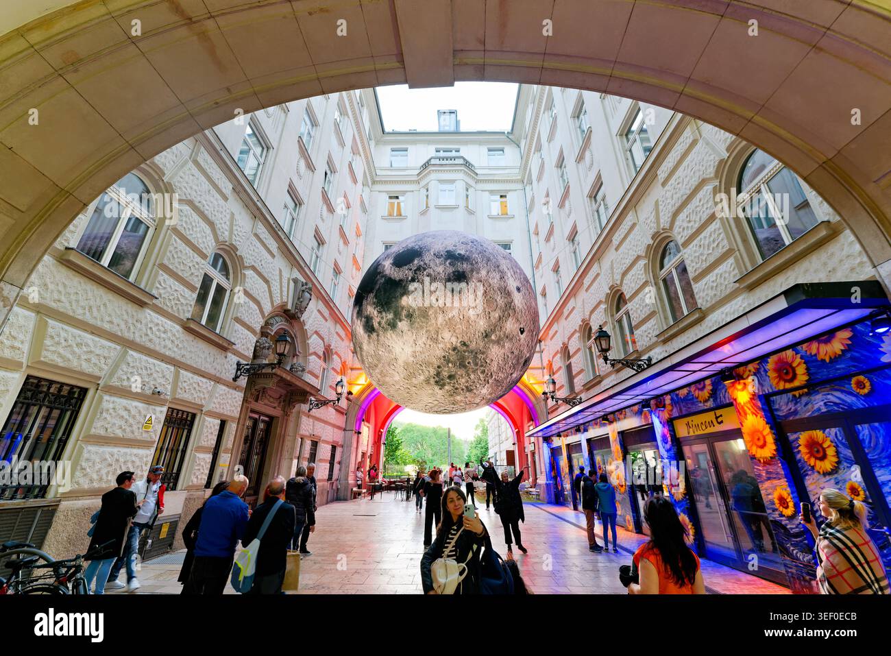 La gente cammina sotto una grande scultura lunare nelle strade della città di Budapest. La scultura crea una vista unica nell'area urbana. Foto Stock
