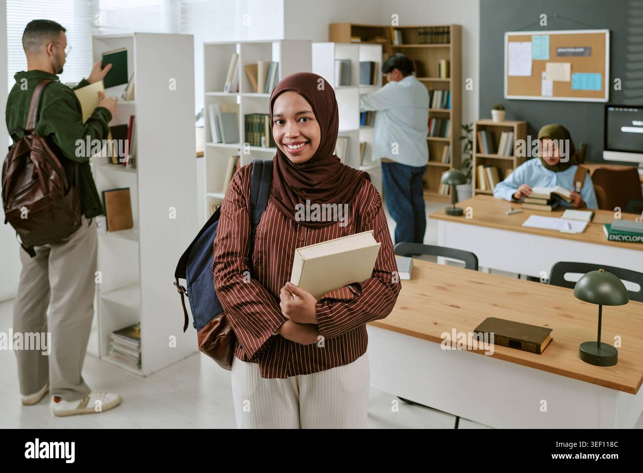 Ritratto di studenti asiatici che tengono libri in biblioteca Foto Stock