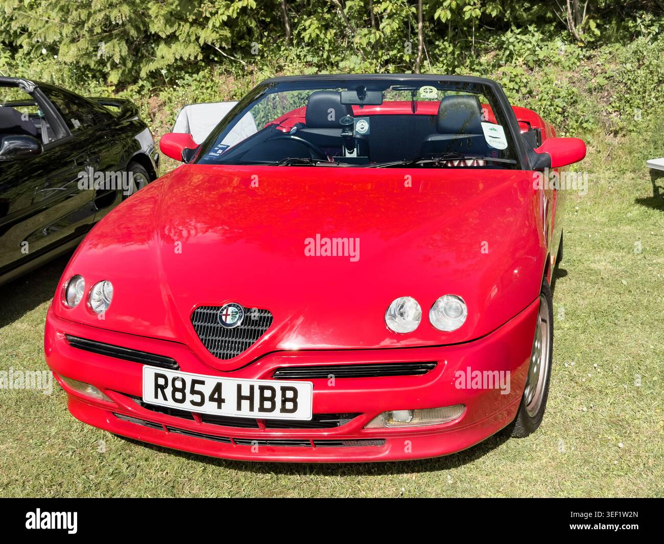 Rossa Alfa Romeo Spider 916 convertibile con registrazione UK R854 HBB parcheggiata sull'erba in un salone di auto d'epoca nel Regno Unito - Immagine stock catturata con smartphone