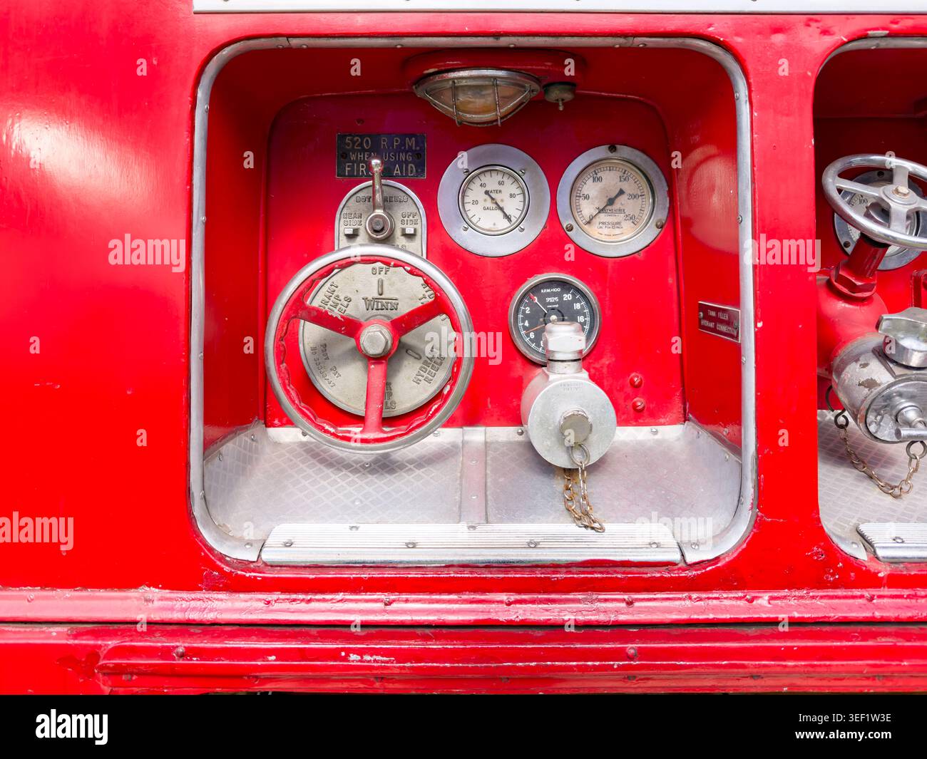 Pannello laterale dettagliato di un pompiere rosso vintage con indicatori analogici e valvola di controllo Winn in un vano incassato - Immagine stock catturata con smartphone