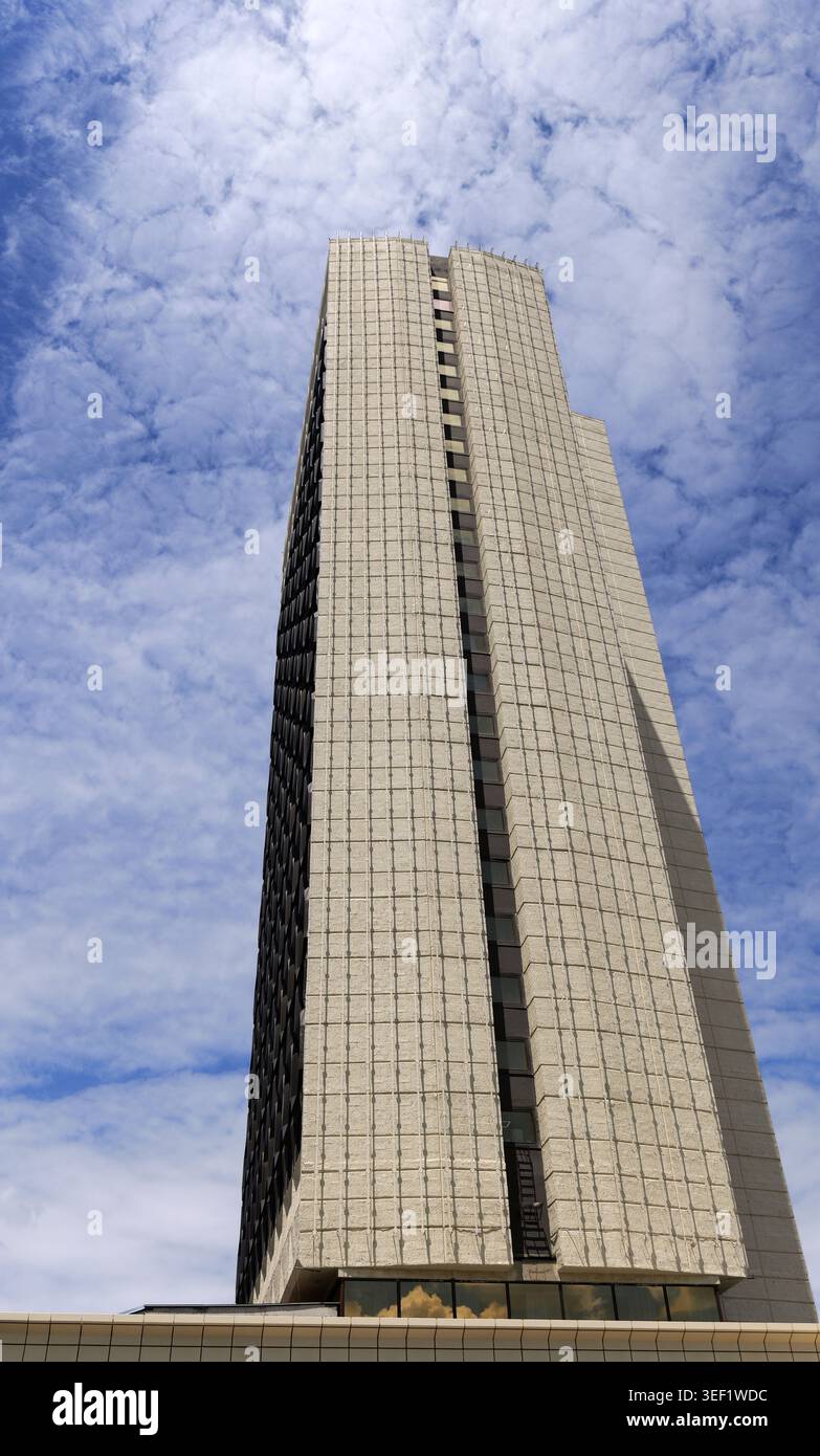 Moderno edificio per uffici che si innalza in un cielo blu luminoso pieno di nuvole bianche e toste, che rappresentano lo sviluppo urbano, gli affari e il contemporaneo Foto Stock