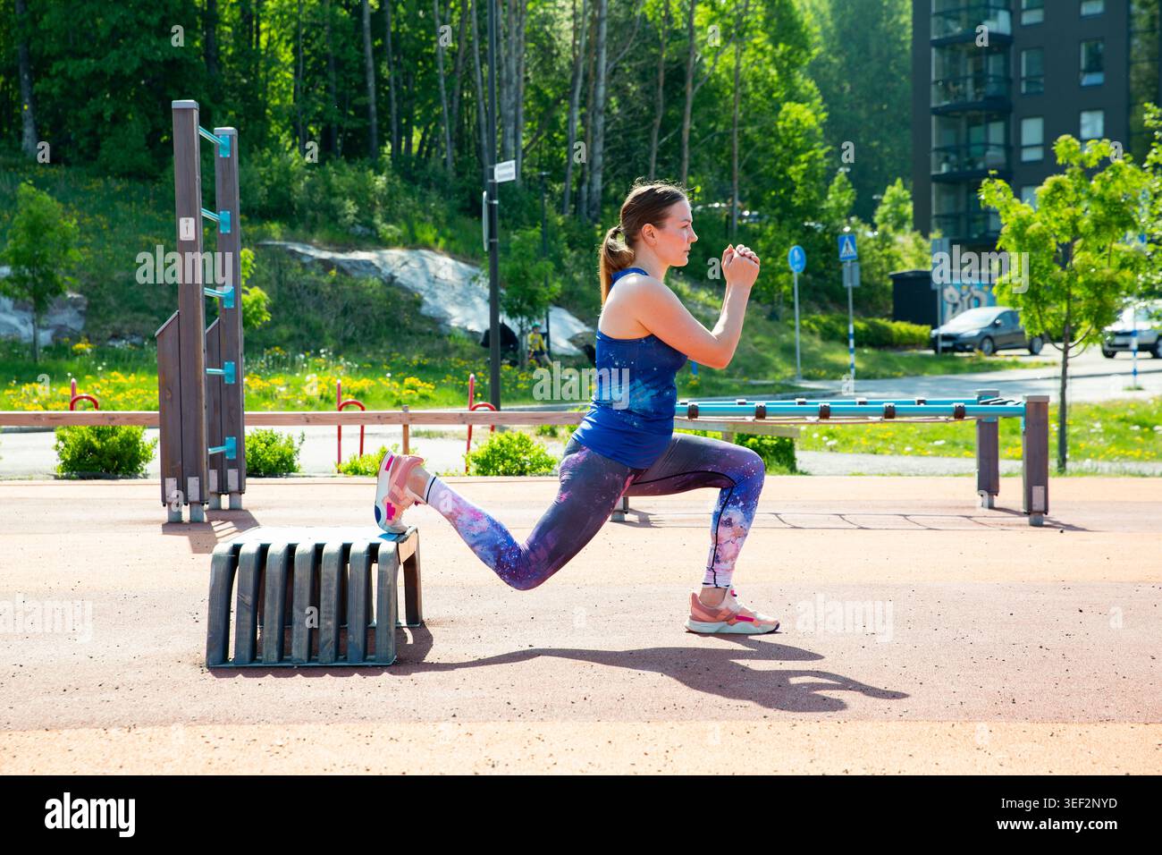 Atleta che fa squat bulgari divisi su una panchina in un campo sportivo all'aperto. Routine di fitness urbana per chiarezza mentale e forza corporea. Foto Stock