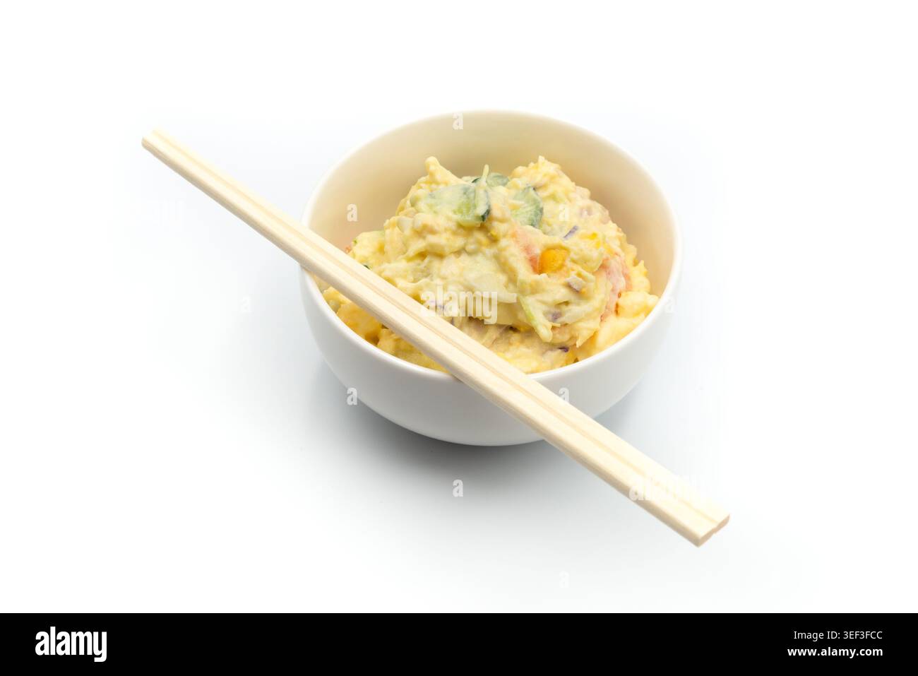 Fotografia gastronomica minimale di una ciotola di insalata di patate in stile giapponese con bacchette di legno isolate su uno sfondo bianco pulito. Foto Stock