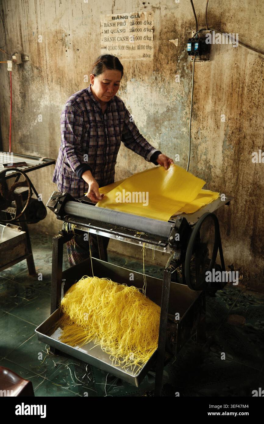 Donna che produce spaghetti freschi utilizzando la tradizionale macchina per pasta manuale in una piccola fabbrica di spaghetti a conduzione familiare, Nha Trang Vietnam 2026 Foto Stock