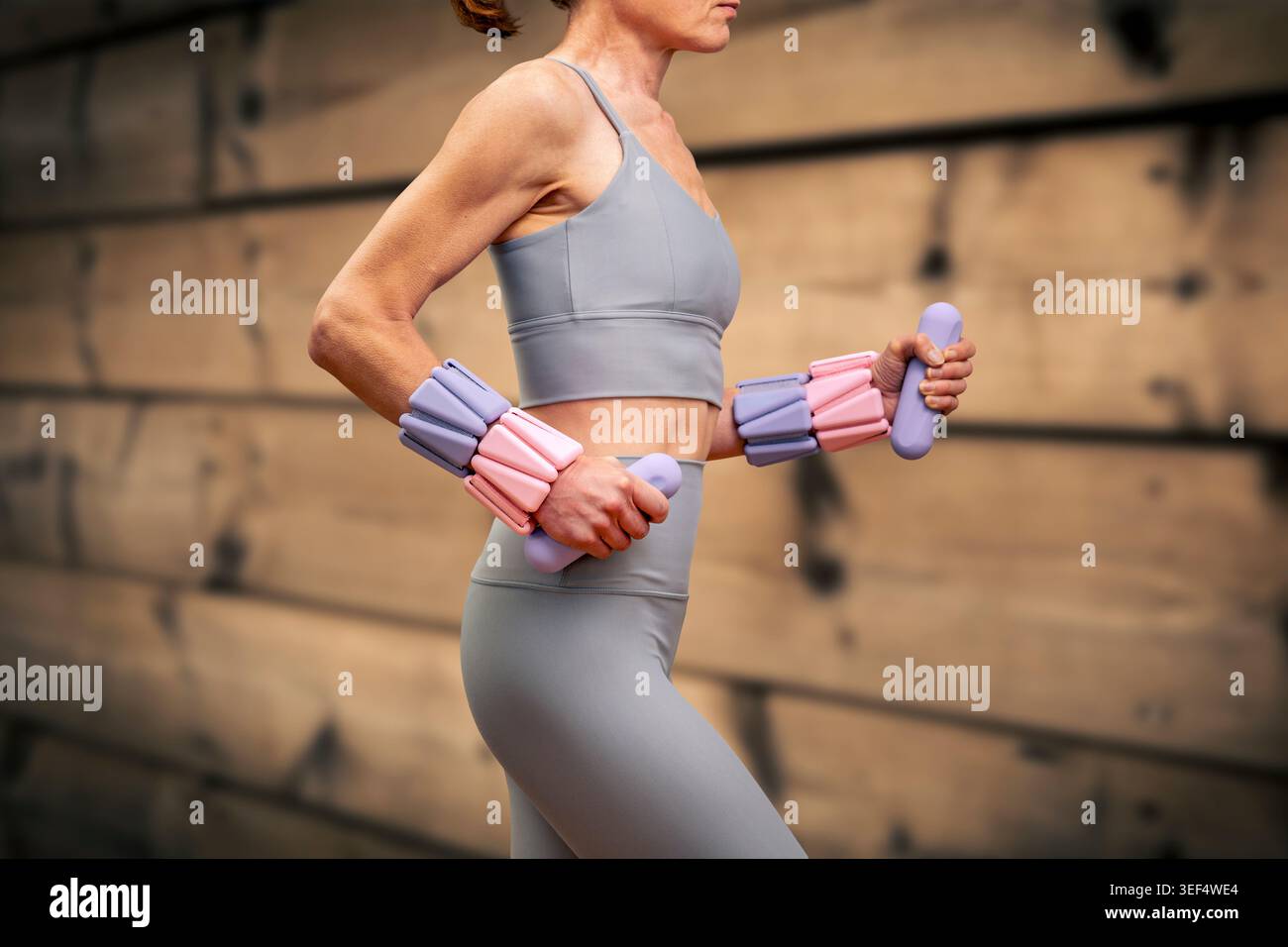 Donna sportiva che indossa pesi da polso regolabili e utilizza pesi a mano Foto Stock