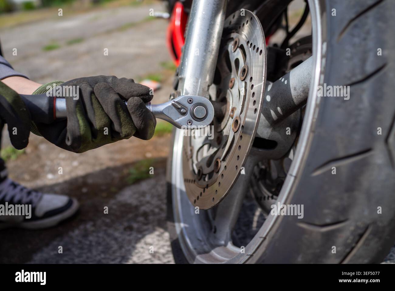 Primo piano, allentamento meccanico del dado della ruota con chiave a bussola, battistrada e cerchione visibili, azione energica della mano Foto Stock