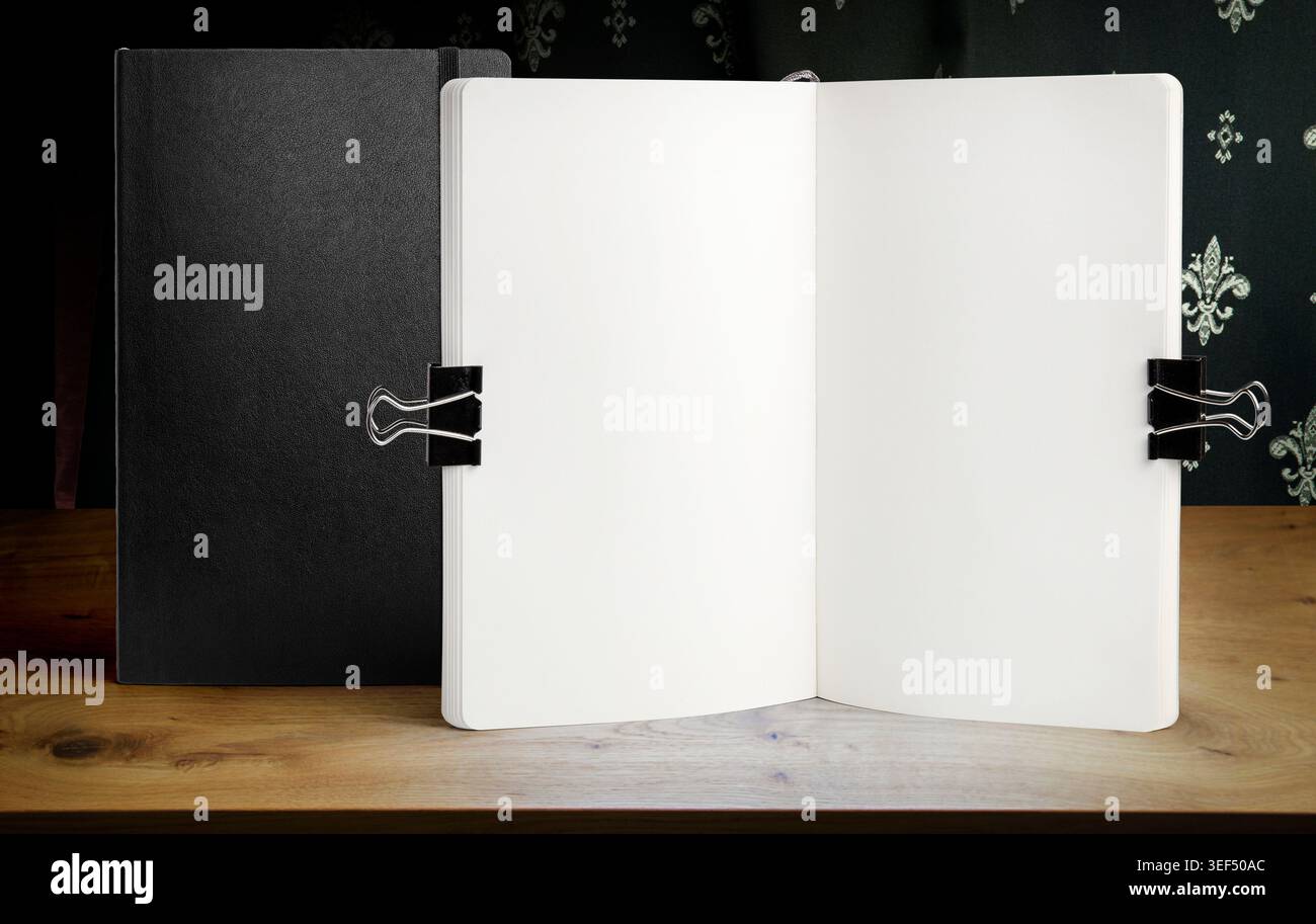 Apri il modello bianco del notebook su un tavolo in legno con clip per ufficio e piante decorative. Schema di schizzo o modello di menu in un'area di lavoro luminosa Foto Stock