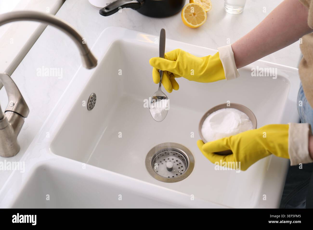 Donna che usa bicarbonato di sodio per disintasare lo scarico del lavandino, primo piano Foto Stock
