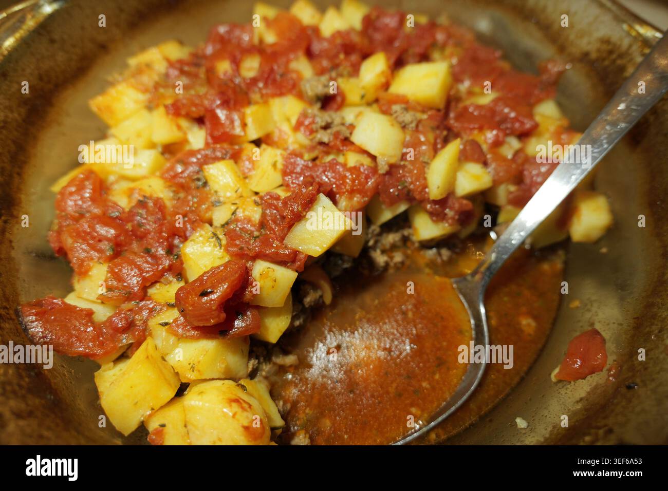 Sostanziosa casseruola al forno di carne macinata condita, pomodori a dadini e patate dorate, calda e pronta per essere servita con un cucchiaio di cibo salato Foto Stock