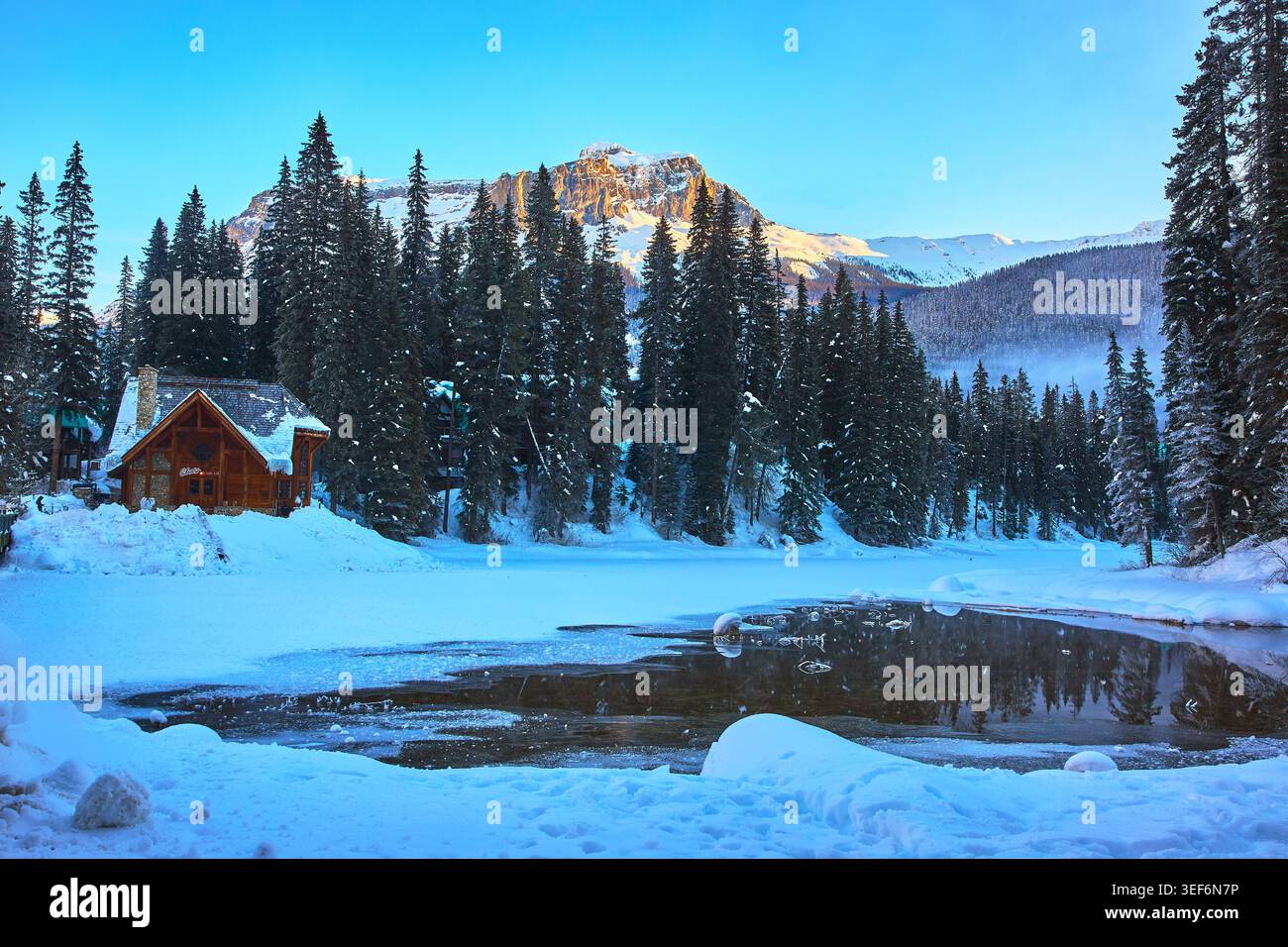 Winter Lodge Forest e Mountain Reflections accanto al lago Frozen Foto Stock
