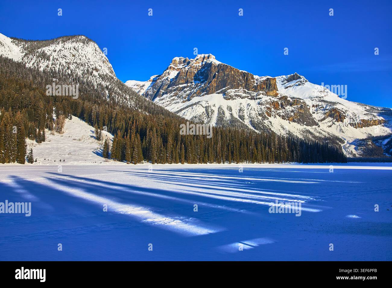 Montagne innevate, foresta Evergreen e lago ghiacciato alla luce d'inverno Foto Stock
