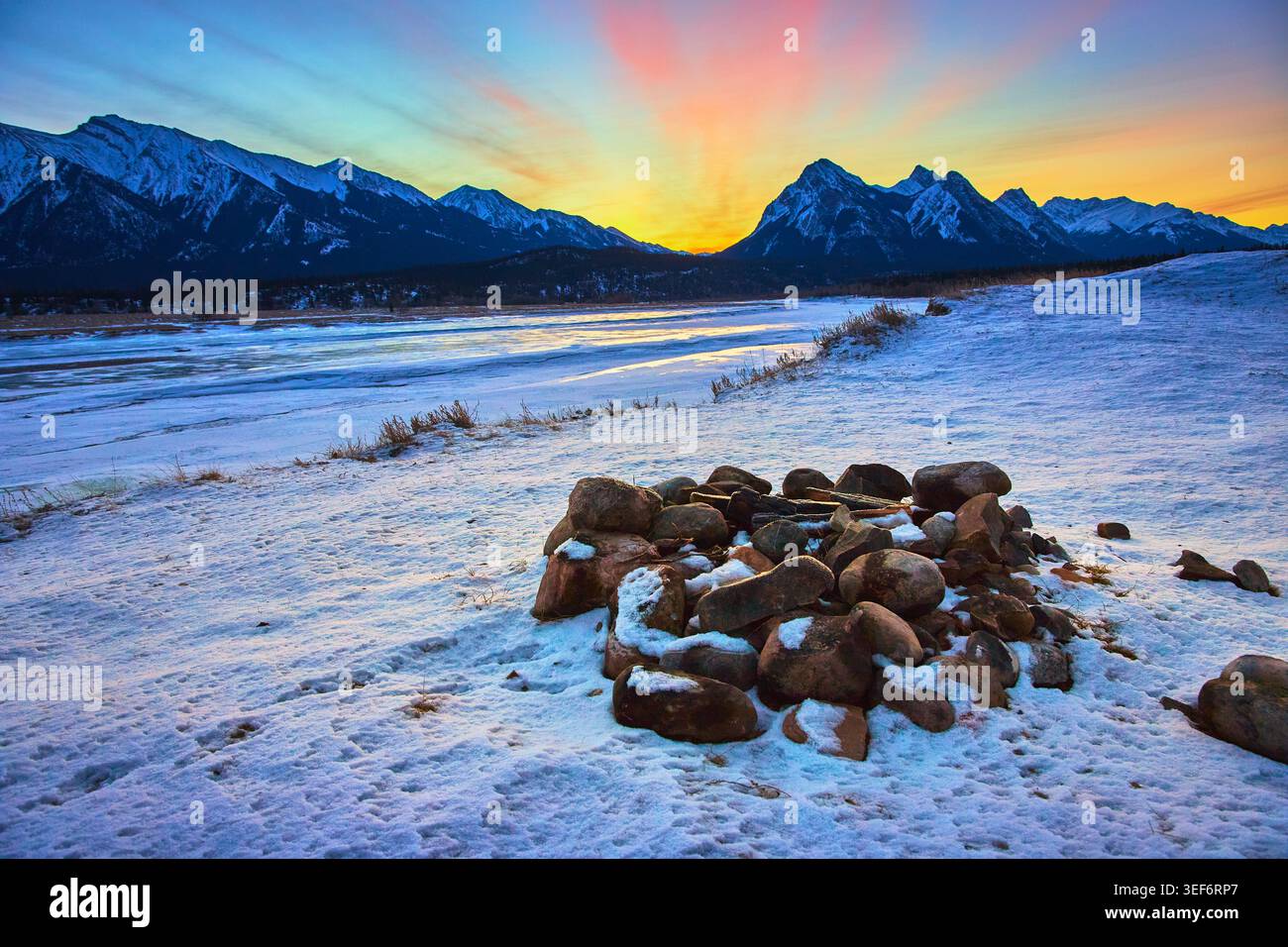 Falò all'alba d'inverno e Montagne Rocciose sul fiume Frozen nell'Alberta Canada Foto Stock