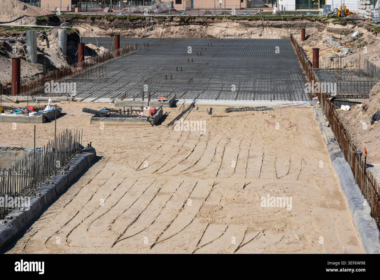 Vista di un cantiere preparato che mostra il livellamento della sabbia, il terreno e la rete di rinforzo in acciaio pronta per il versamento di fondazioni in calcestruzzo Foto Stock