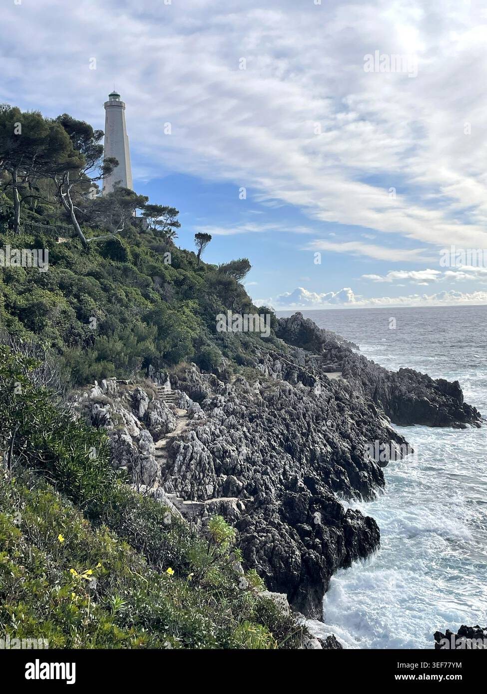 Saint-Jean-Cap-Ferrat, Francia. Il sentiero costiero Chemin des Douaniers, con il faro Phare du Cap Ferrat) in lontananza. Foto Stock