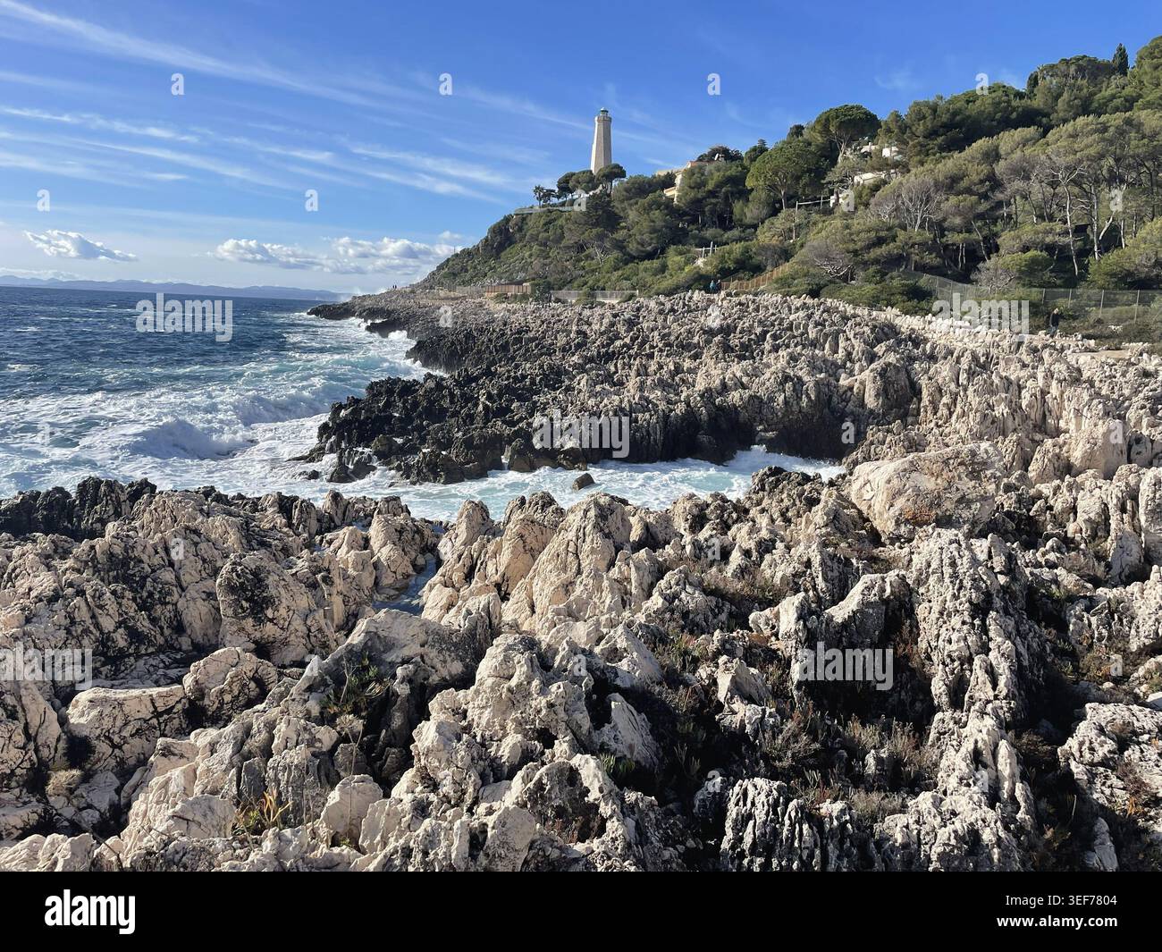 Saint-Jean-Cap-Ferrat, Francia. Il sentiero costiero Chemin des Douaniers, con il faro Phare du Cap Ferrat) in lontananza. Foto Stock