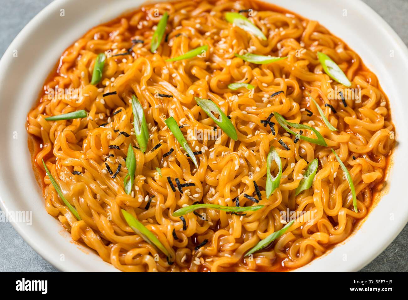 Spaghetti al Ramen istantanei piccanti in una ciotola con Scallions Foto Stock