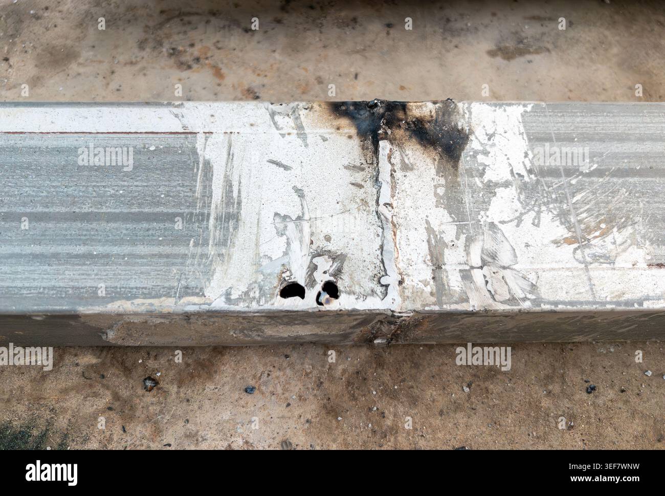 Primo piano di una struttura metallica danneggiata che mostra difetti del giunto di saldatura, segni di ustioni, corrosione e graffi superficiali. Concetto industriale di guasto, riparazione, Foto Stock