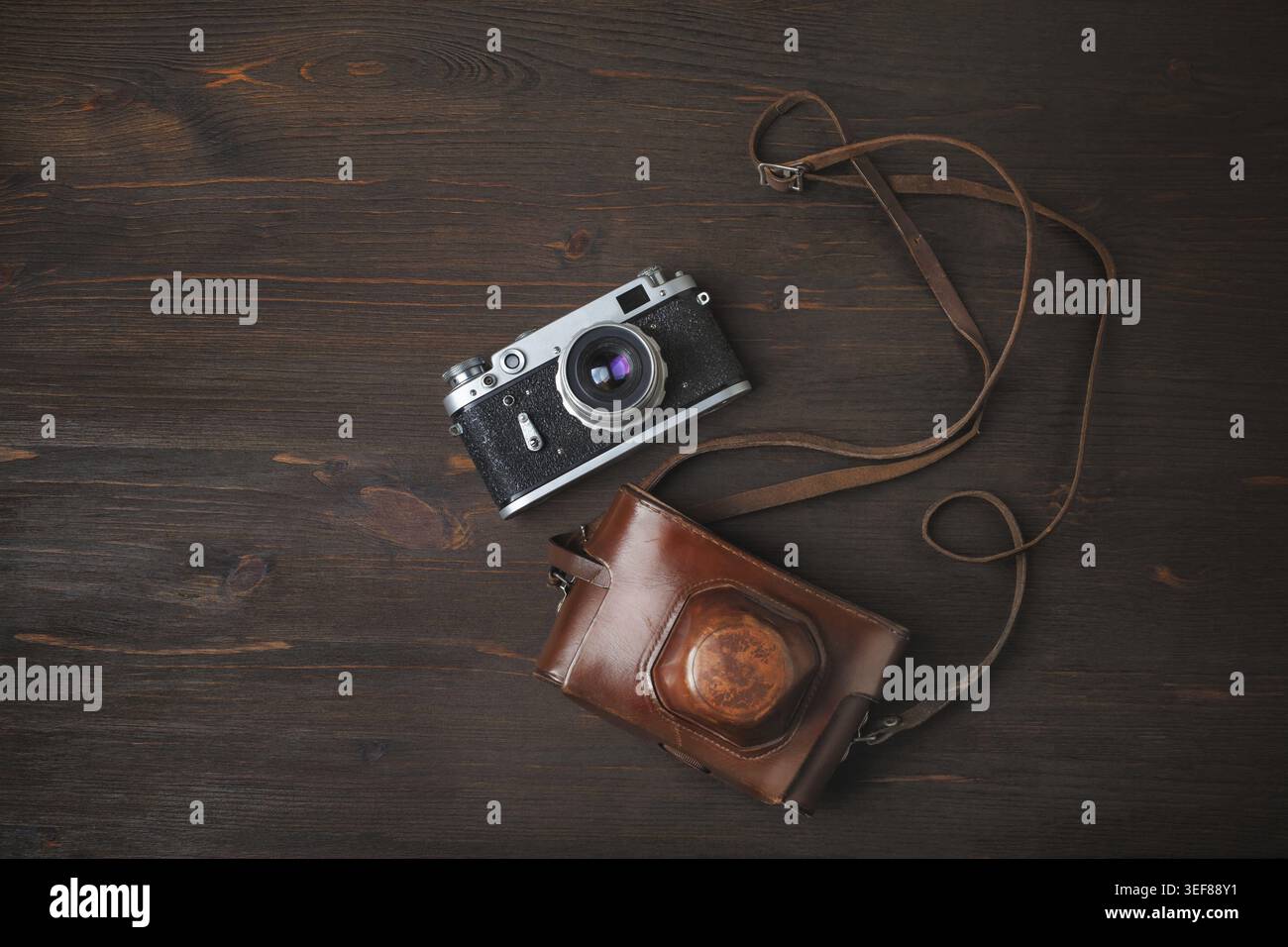 Fotocamera retrò e custodia su sfondo di legno. Posizione piatta Foto Stock