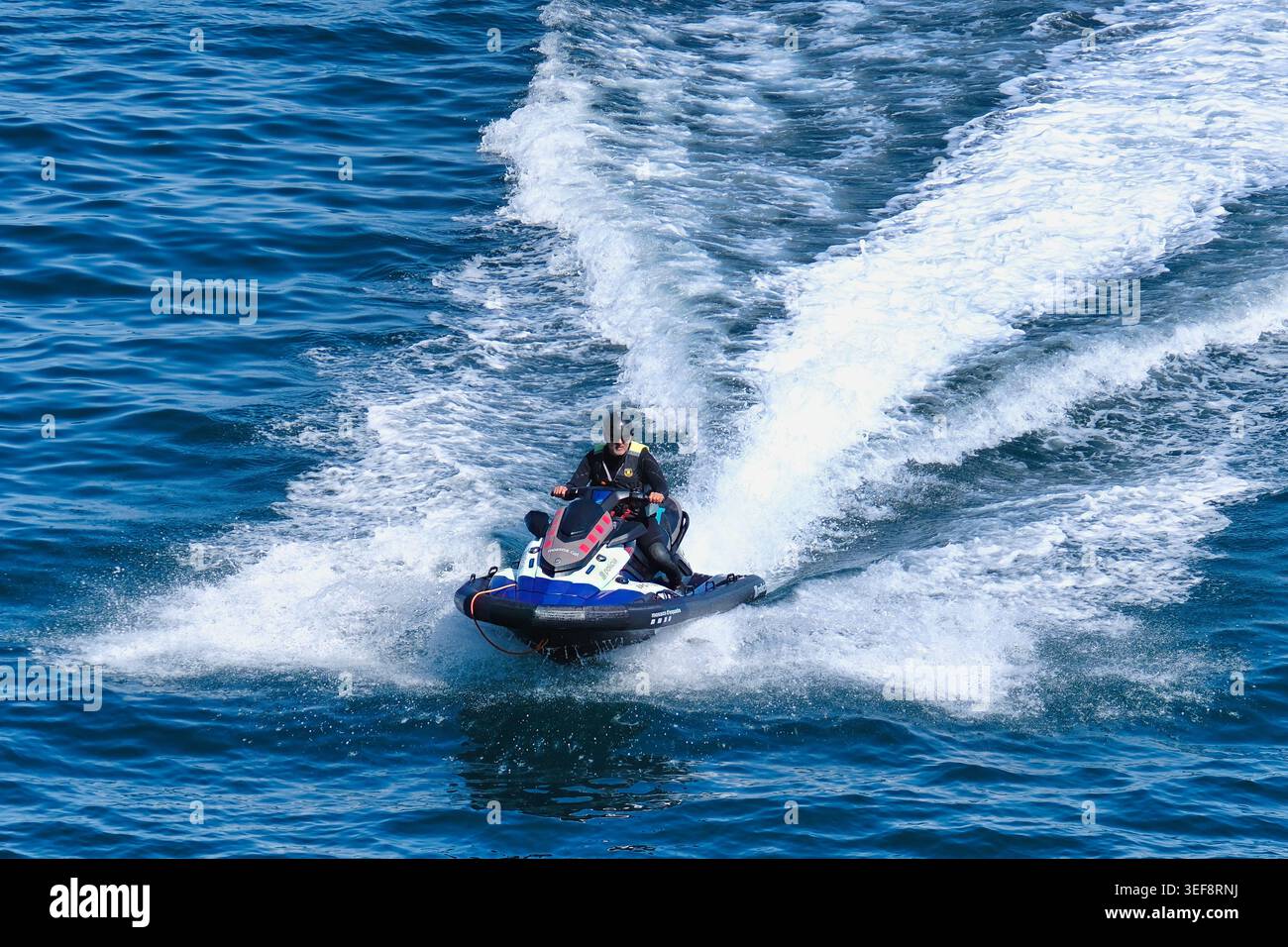 12.05.25 l'Escala Girona Spagna – Guardiano delle onde: Un agente di polizia sfreccia sull'acqua su una moto d'acqua ad alta potenza, tagliando attraverso il mare con la p Foto Stock