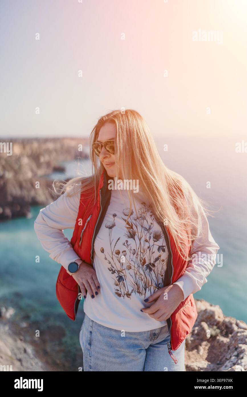 La scogliera della donna si trova al limitare di una vista panoramica della costa durante il tramonto con spazio per copiare Foto Stock