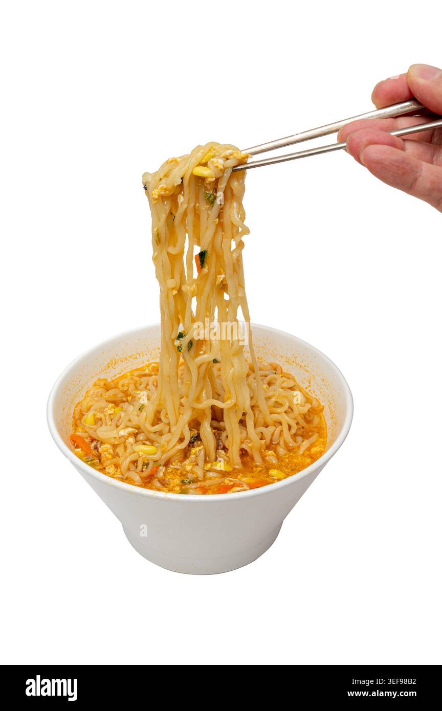 mani che tengono le bacchette con spaghetti istantanei coreani in una ciotola bianca isolata su sfondo bianco Foto Stock