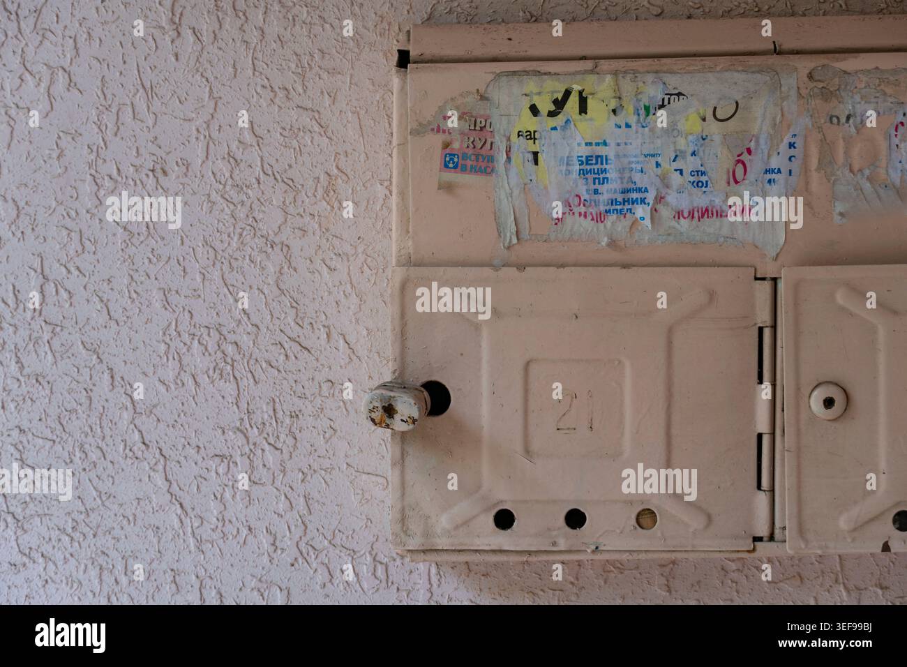 Cassette postali in metallo vintage montate su una parete testurizzata nel corridoio del vecchio edificio di appartamenti. Dettagli urbani residenziali con superfici usurate ed estetica retrò Foto Stock