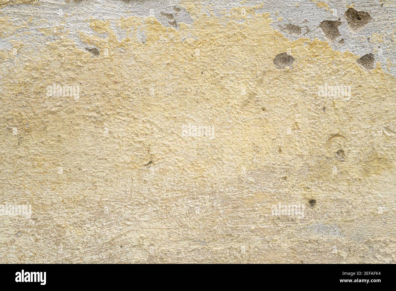 Scheggiatura di vernice gialla su pareti in pietra bianca Foto Stock
