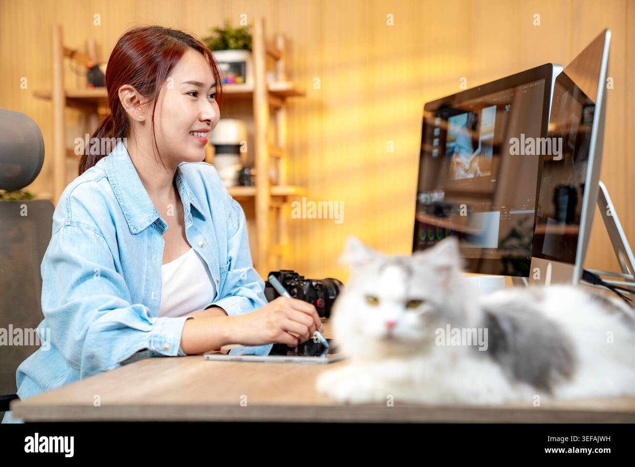 Una donna professionista modifica filmati in uno studio domestico, illustrando la flessibilità e la gestione del tempo di una carriera creativa freelance. Foto Stock