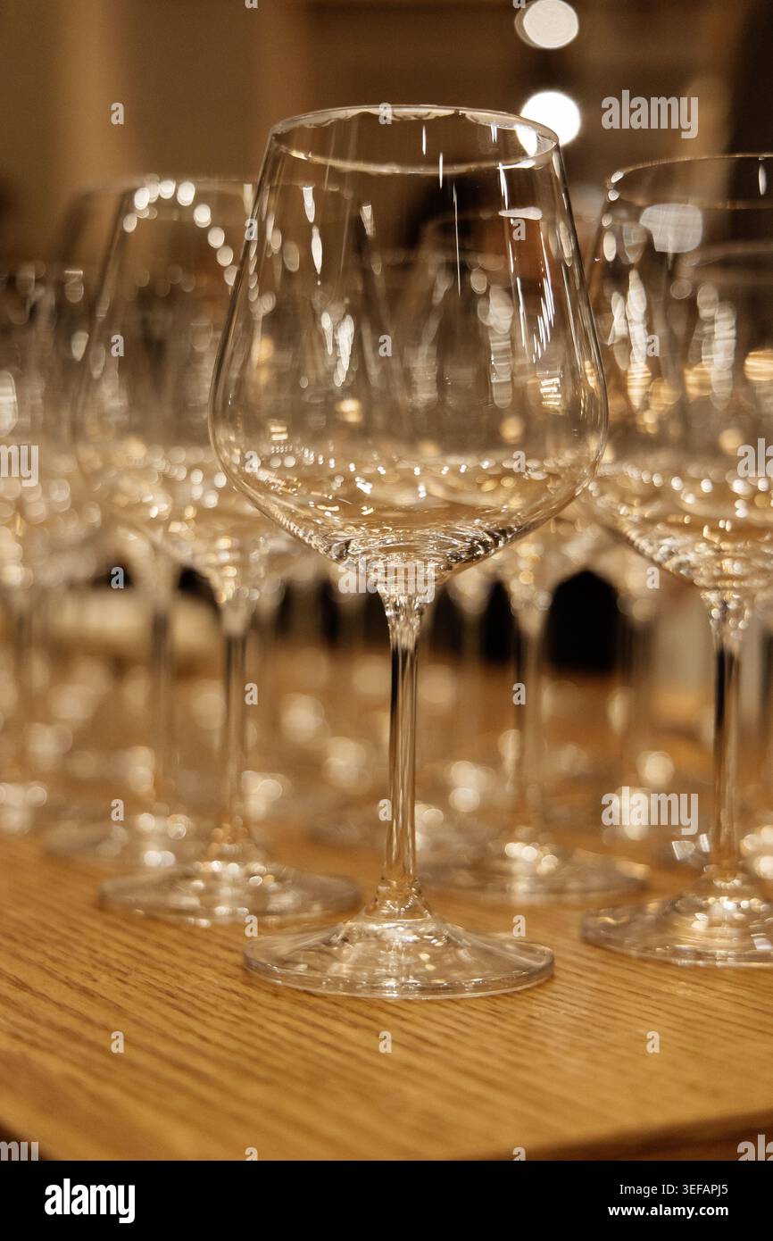Eleganti bicchieri da vino su tavolo in legno nella calda luce del ristorante Foto Stock